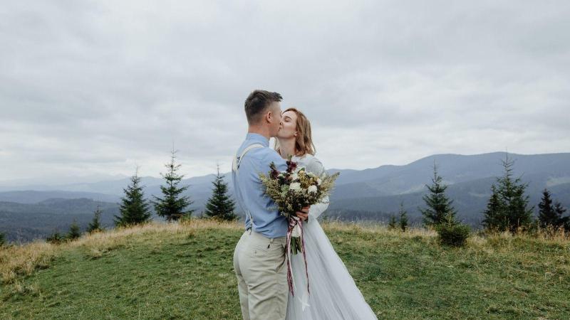 Mladý pár si dává první svatební pusu na vrcholku hor, svatební sezona.