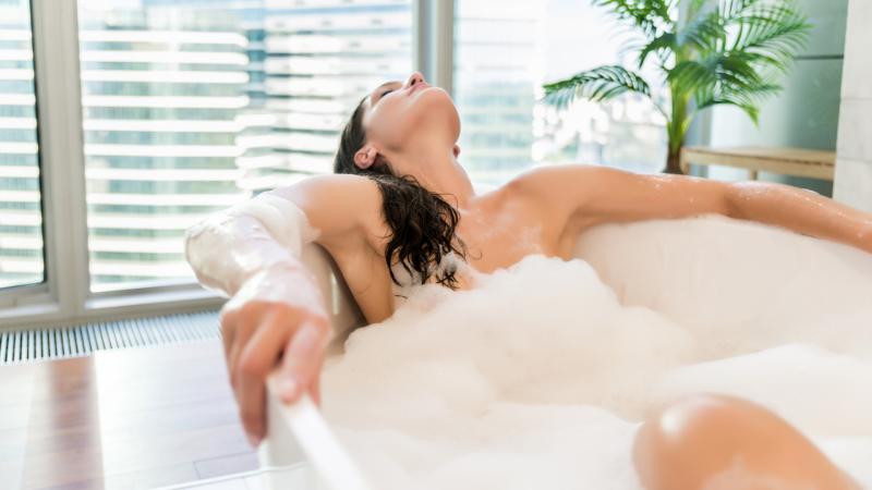 Žena relaxuje ve vaně s pěnou.