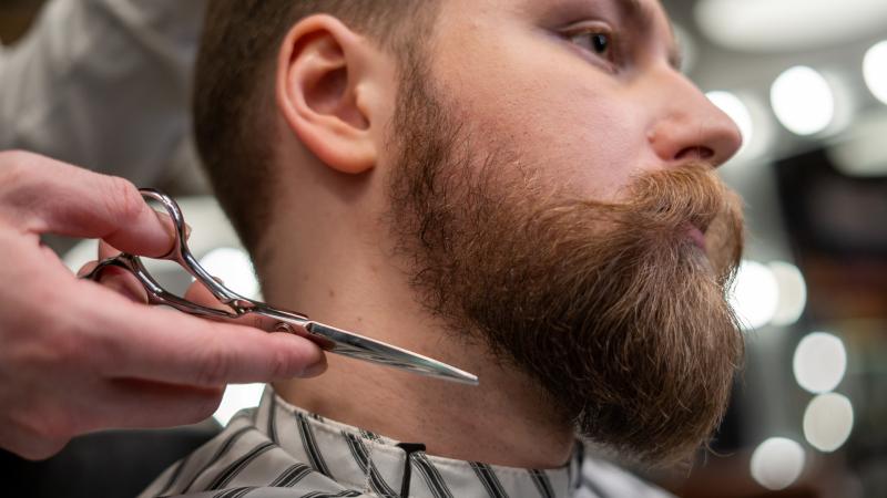 Muž si nechá zastřihávat vousy v barbershopu