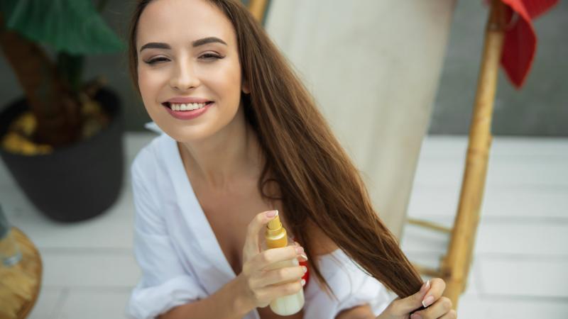 Žena s dlouhými vlasy nanáší olej na rozčesávání vlasů